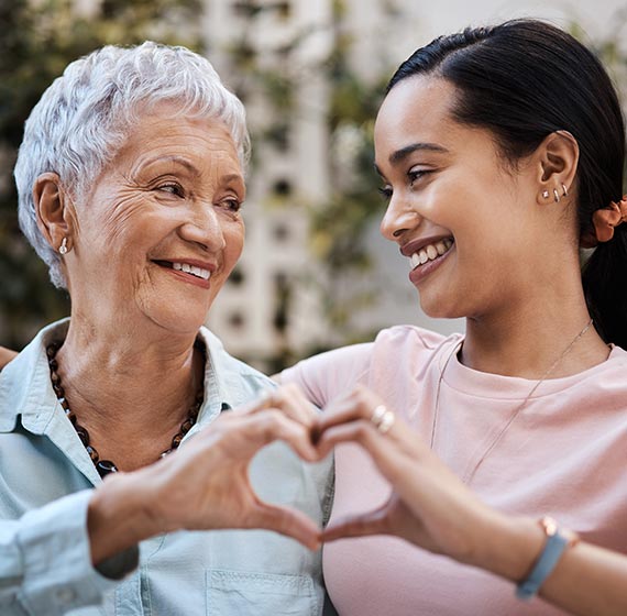 Mother and daughter making a heart symbol with their hands